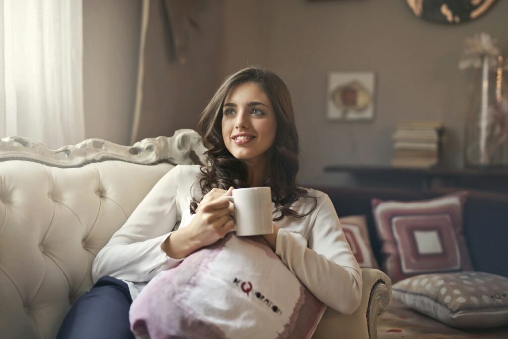 A woman and man sit close together on a white sofa, smiling at each other.