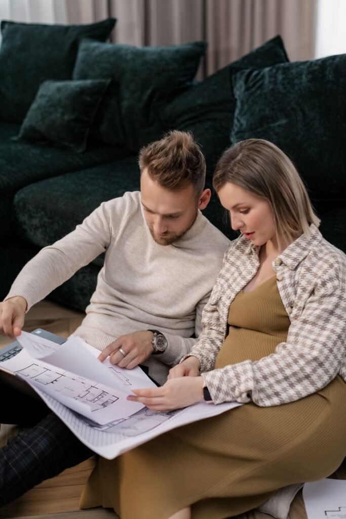 “A man and woman seated together reviewing printed floor plans.”
