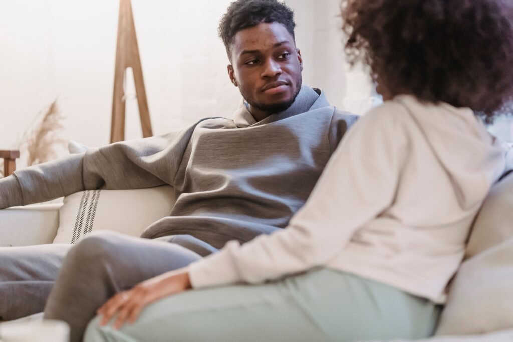 Man sitting on a sofa and listening attentively to a woman during a serious conversation at home.