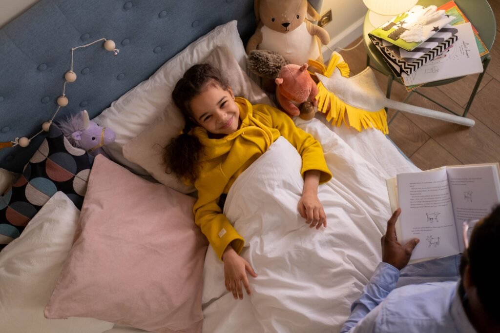 Child lying in bed while an adult holds an open book beside her