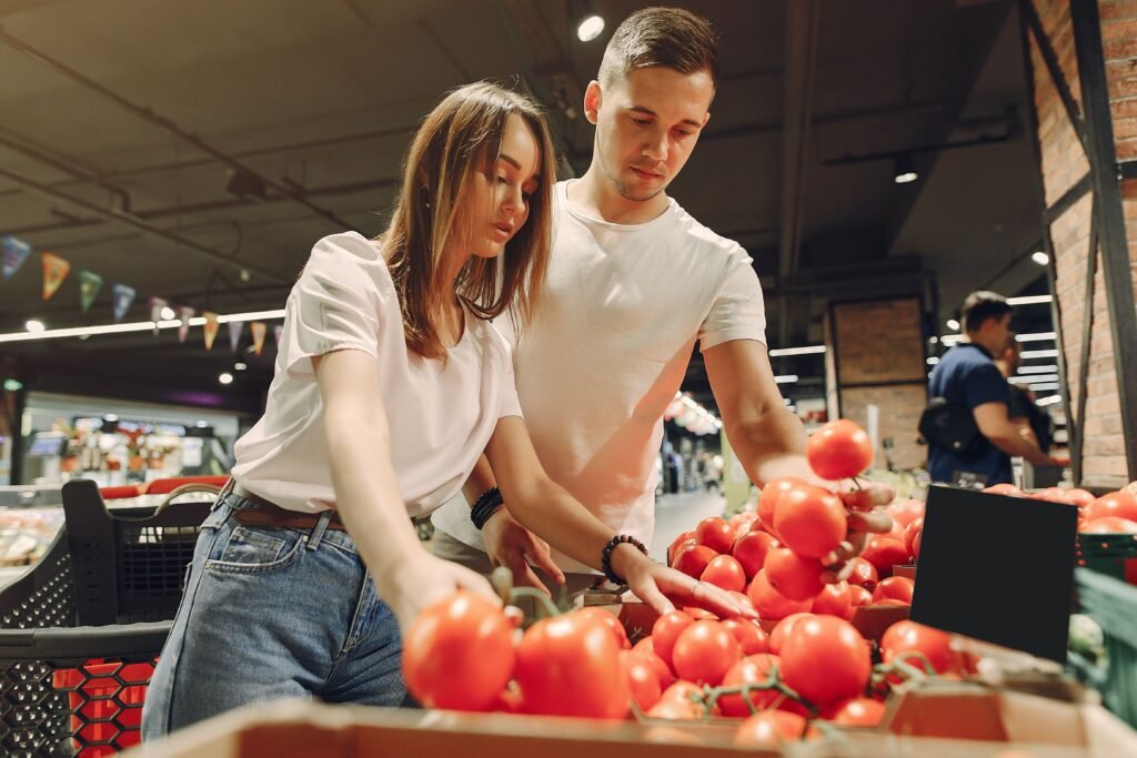 Couple shopping together at a supermarket, selecting fresh tomatoes from the produce section.