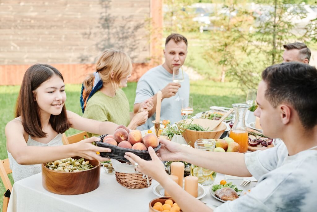 “A group sharing food around an outdoor dining table.”
