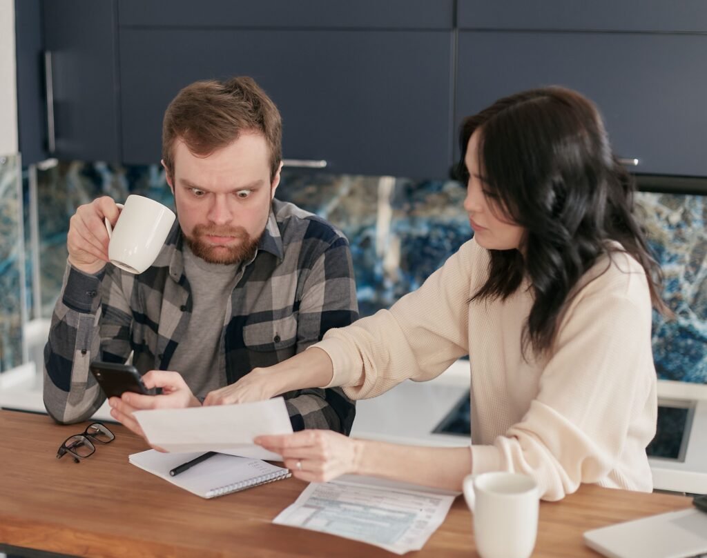 Couple reviewing paperwork and a phone at their kitchen table