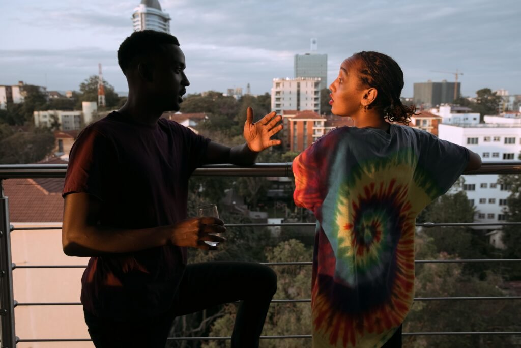 Two people talking on a balcony overlooking the city