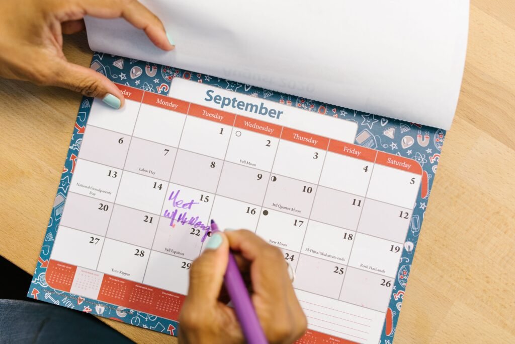 Person writing on a paper calendar with a purple pen