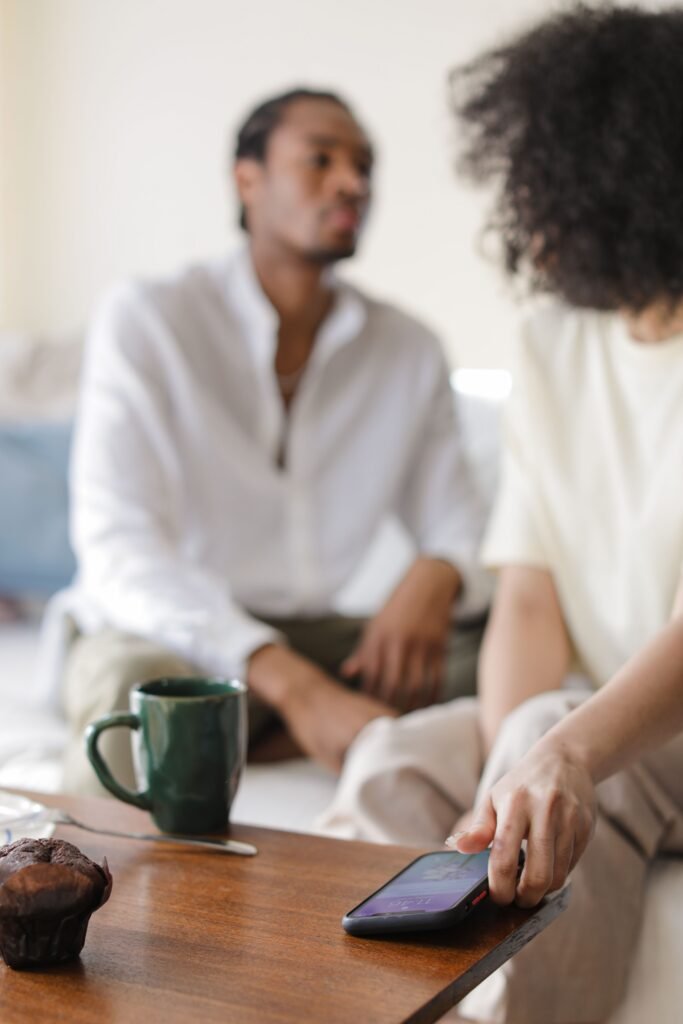 Woman touching a smartphone on a coffee table while seated beside a man.
