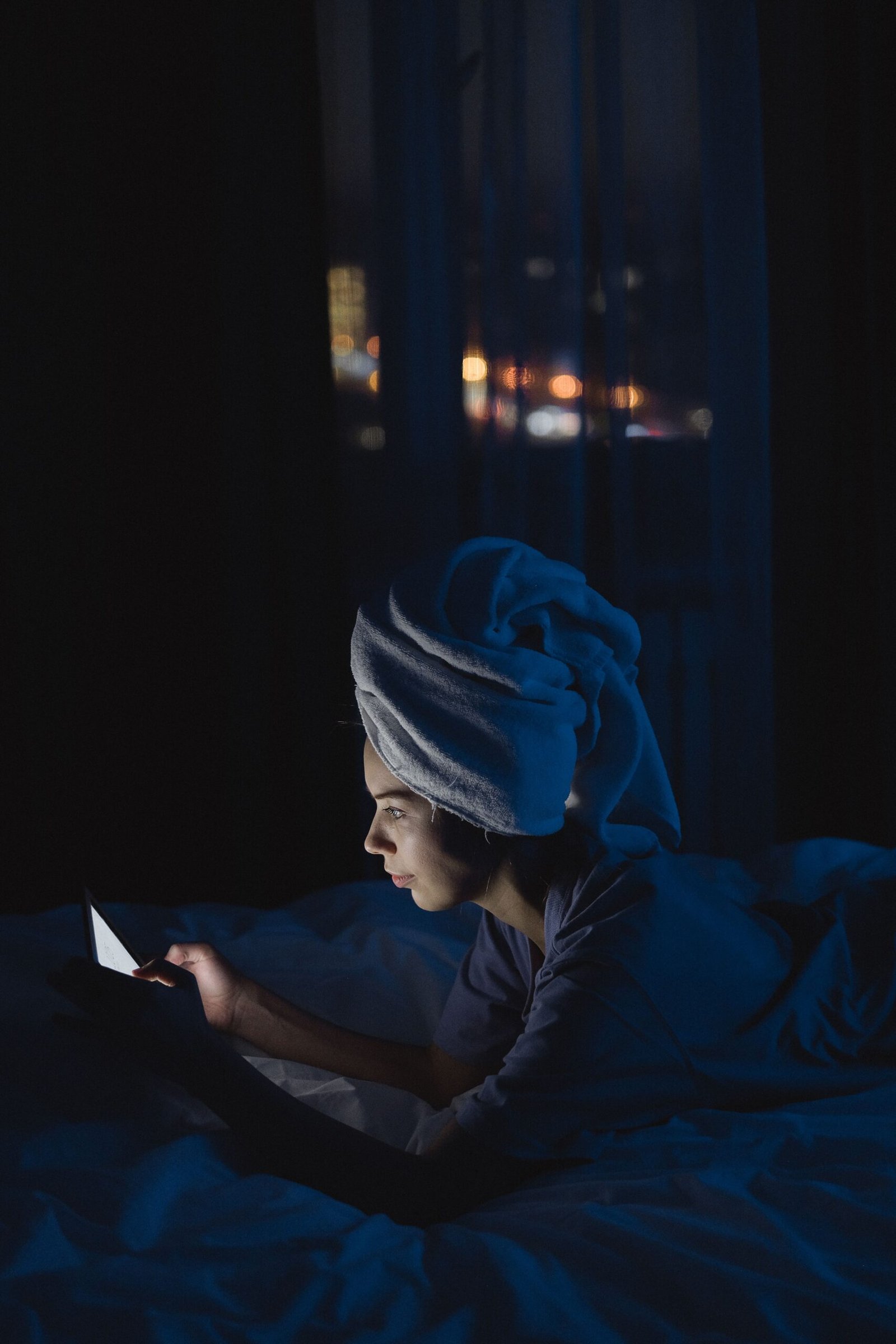 A woman looks at her phone in a dark room at night.