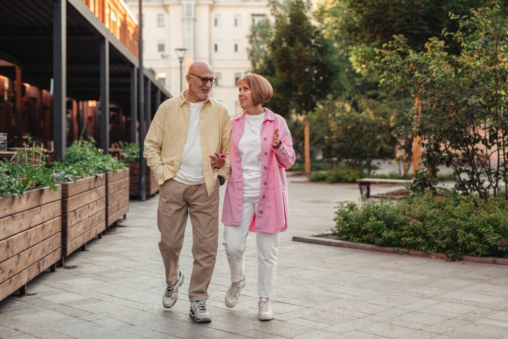 Man and woman walking side by side outdoors, looking at each other as the woman gestures while talking.