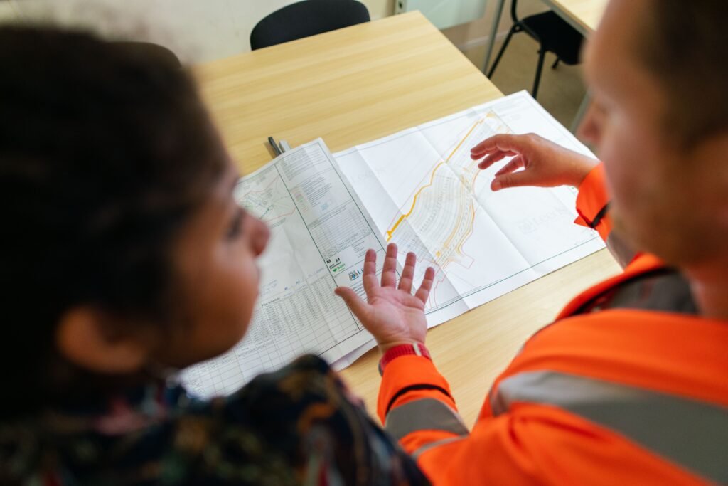 Two engineers review plans spread across a table.